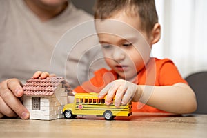 Dad and son play with a house and a school bus. Spending time with children.