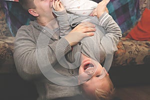 Dad and son play, indulge. The father turned his son upside down, the child laughs