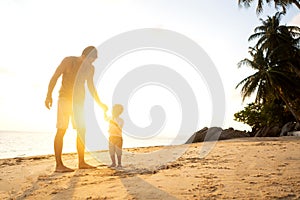 Dad and son playing on the sand at the beach at sunset