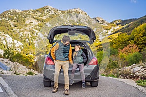 Dad and son are resting on the side of the road on a road trip. Road trip with children concept