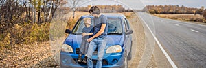 Dad and son are resting on the side of the road on a road trip. Road trip with children concept BANNER, LONG FORMAT