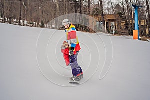 Dad and son ride the same snowboard, breaking safety precautions