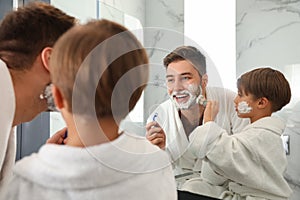 Dad and son with shaving foam on their faces having fun