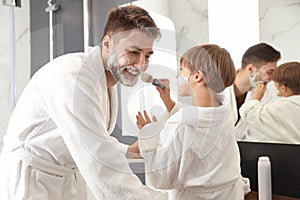 Dad and son with shaving foam on their faces having fun