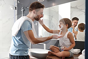 Dad and son with shaving foam on their faces having fun