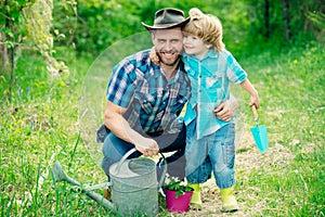 Dad and son spending free time together in garden and hugging. Son helping his father to plant the tree while working