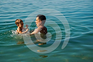 Dad and son splashing in the water merrily. Summer family vacations