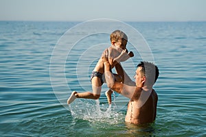 Dad and son splashing in the water merrily. Summer family vacations