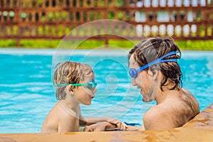 Dad and son in swimming Goggles have fun in the pool