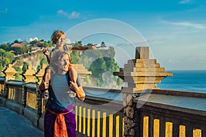 Dad and son travelers in Pura Luhur Uluwatu temple, Bali, Indonesia. Amazing landscape - cliff with blue sky and sea