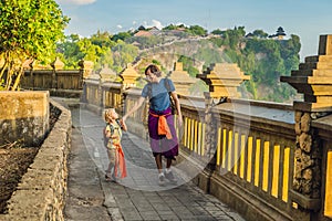 Dad and son travelers in Pura Luhur Uluwatu temple, Bali, Indonesia. Amazing landscape - cliff with blue sky and sea. Traveling wi