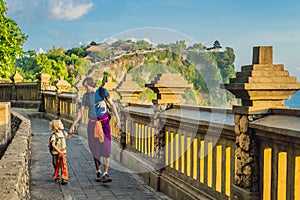 Dad and son travelers in Pura Luhur Uluwatu temple, Bali, Indonesia. Amazing landscape - cliff with blue sky and sea. Traveling wi