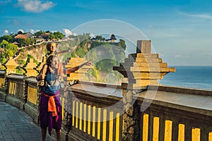 Dad and son travelers in Pura Luhur Uluwatu temple, Bali, Indonesia. Amazing landscape - cliff with blue sky and sea. Traveling wi