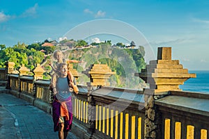 Dad and son travelers in Pura Luhur Uluwatu temple, Bali, Indonesia. Amazing landscape - cliff with blue sky and sea. Traveling wi