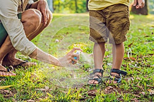 Dad and son use mosquito spray.Spraying insect repellent on skin outdoor photo