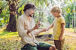 Dad and son use mosquito spray.Spraying insect repellent on skin outdoor