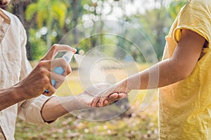 Dad and son use mosquito spray.Spraying insect repellent on skin outdoor