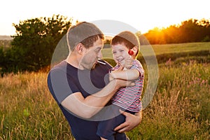 Dad and son walk in a yellow summer field in the evening at sunset and eat candy on a stick. Father`s Day, love in the family, th