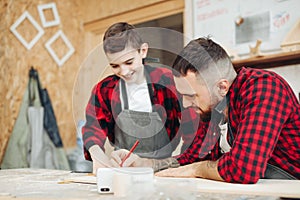 Dad and son in the workshop playing designing a model of a wooden plane