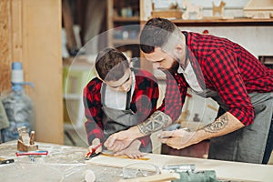 Dad and son in the workshop playing designing a model of a wooden plane