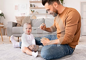 Dad Spoon Feeding Baby During Paternity Leave At Home photo