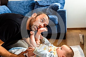 Dad struggling with his baby daughter to change dirty diapers putting faces of effort, concept of fatherhood