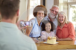 Dad Takes Photo As Multi-Generation Family Celebrate Granddaughter\'s Birthday At Home With Cake