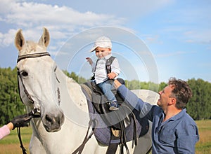 Dad teaches his son to sit in the saddle.