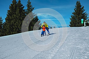 Dad teaches kid gliding behind holding ski poles together