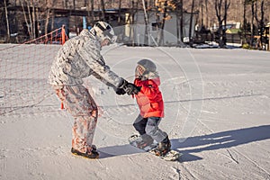 Dad teaches son snowboarding. Activities for children in winter. Children`s winter sport. Lifestyle