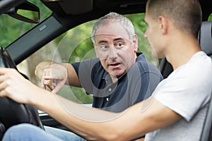 dad teaching son to drive car