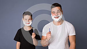 Dad teaching his teen son how shave, standing with razors and shaving foam