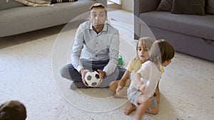 Dad teaching sibling children to throw small soccer ball