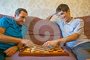 Dad and teenager son play checkers while in quarantine