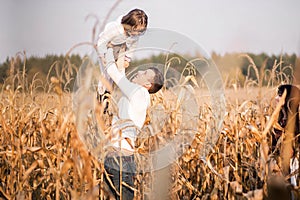 Dad toss daughter up in autumn corn field