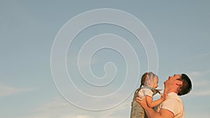 Dad tosses his happy daughter into blue sky. Father and healthy child play together, laugh and hug. carefree kid flies