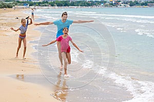 Dad with two children running merrily along the seashore photo