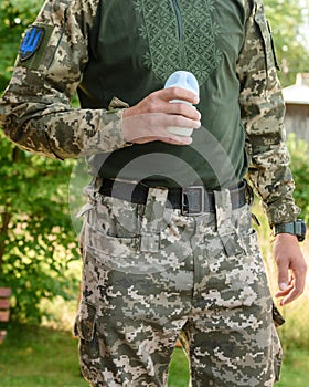 Dad, a Ukrainian military man, holds a baby bottle with milk for the baby.