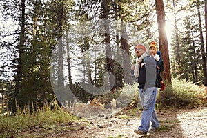 Dad walking in forest with toddler daughter in baby carrier