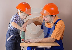 Dad with young son in protective helmet working jigsaw photo