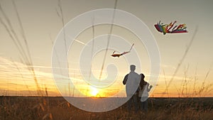 Daddy with children plays with kites against sky in park. Daughter and daddy raise a kite into sky with their hand