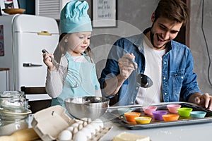 Daddy with daughter baking cake together in home kitchen.