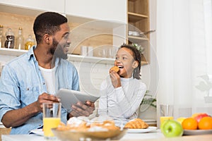 Daddy and daughter eating cookies and checking on new recipe