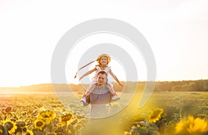 Daddy with daughter walk in the sunflower field and watch the sunset