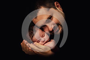 Daddy hugs his newborn baby. Father's love. Close-up portrait on a black background