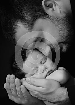 Daddy hugs his newborn baby. Father `s love. Close-up portrait on a black background