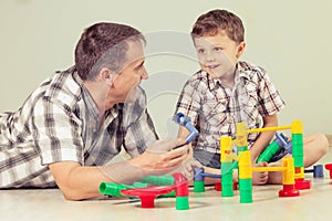 Daddy with little boy playing with toy on the floor at the day