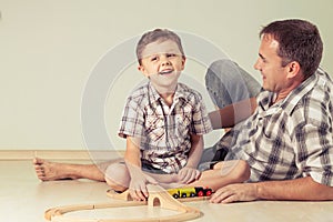 Daddy with little boy playing with toy train on the floor at the