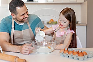 Daddy And Little Daughter Making Dough Baking Cake In Kitchen
