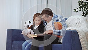 Daddy read a book to her daughter at home. Dream kid coronavirus stay home lockdown concept. Daddy is sitting on the